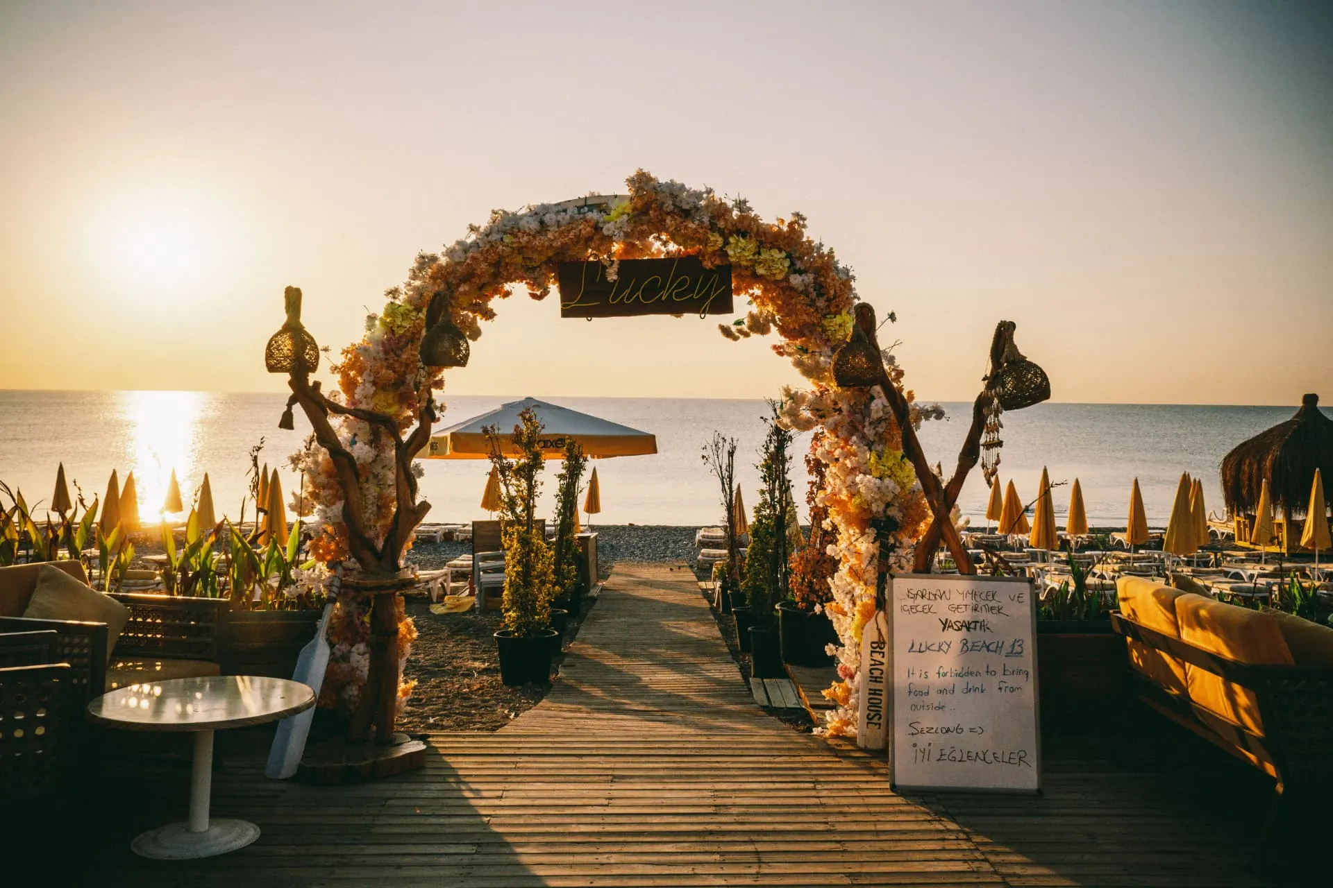 Faux floral arch styled at golden hour for a seaside wedding ceremony